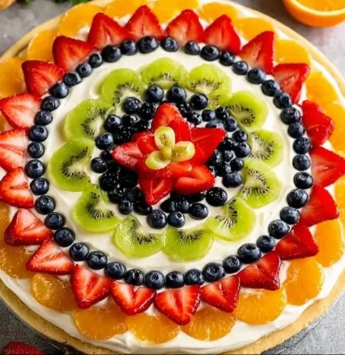 Colorful fruit pizza topped with an array of fresh fruits and creamy frosting