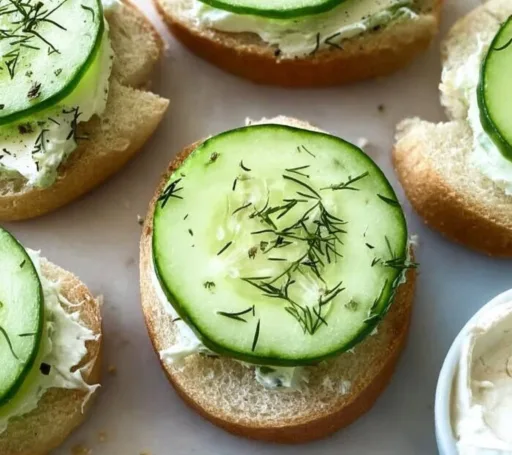 Cucumber cream cheese bites topped with fresh herbs on a serving platter