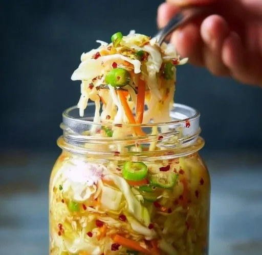 Homemade fermented cabbage sauerkraut in a jar on a wooden table.