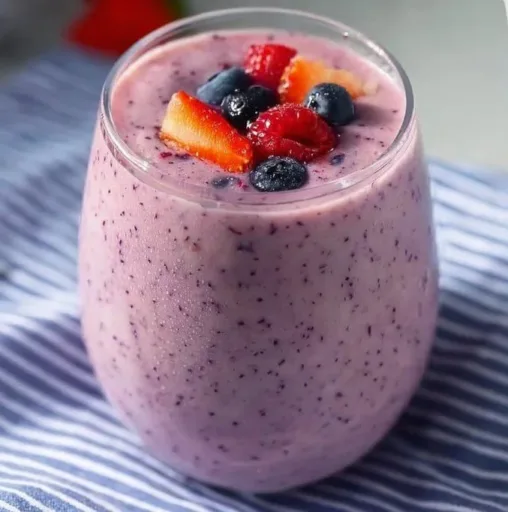 Delicious mixed berry smoothie in a glass with fresh berries on the side