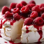 Delicious creamy raspberry pavlova pie topped with fresh raspberries.
