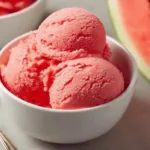 Homemade watermelon ice cream in a bowl garnished with fresh mint leaves.